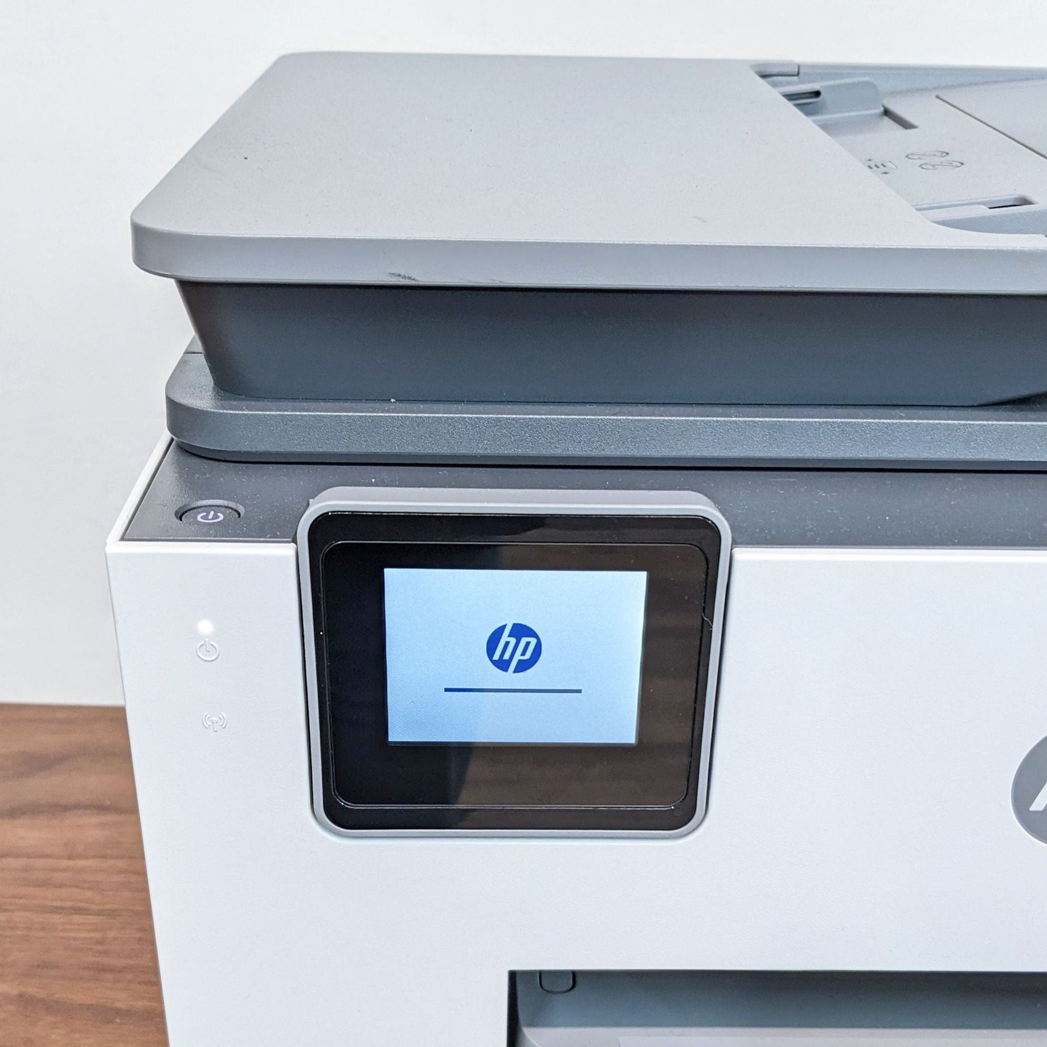 HP All-in-One printer from a side angle with cover closed, highlighting its compact design and touch screen panel.