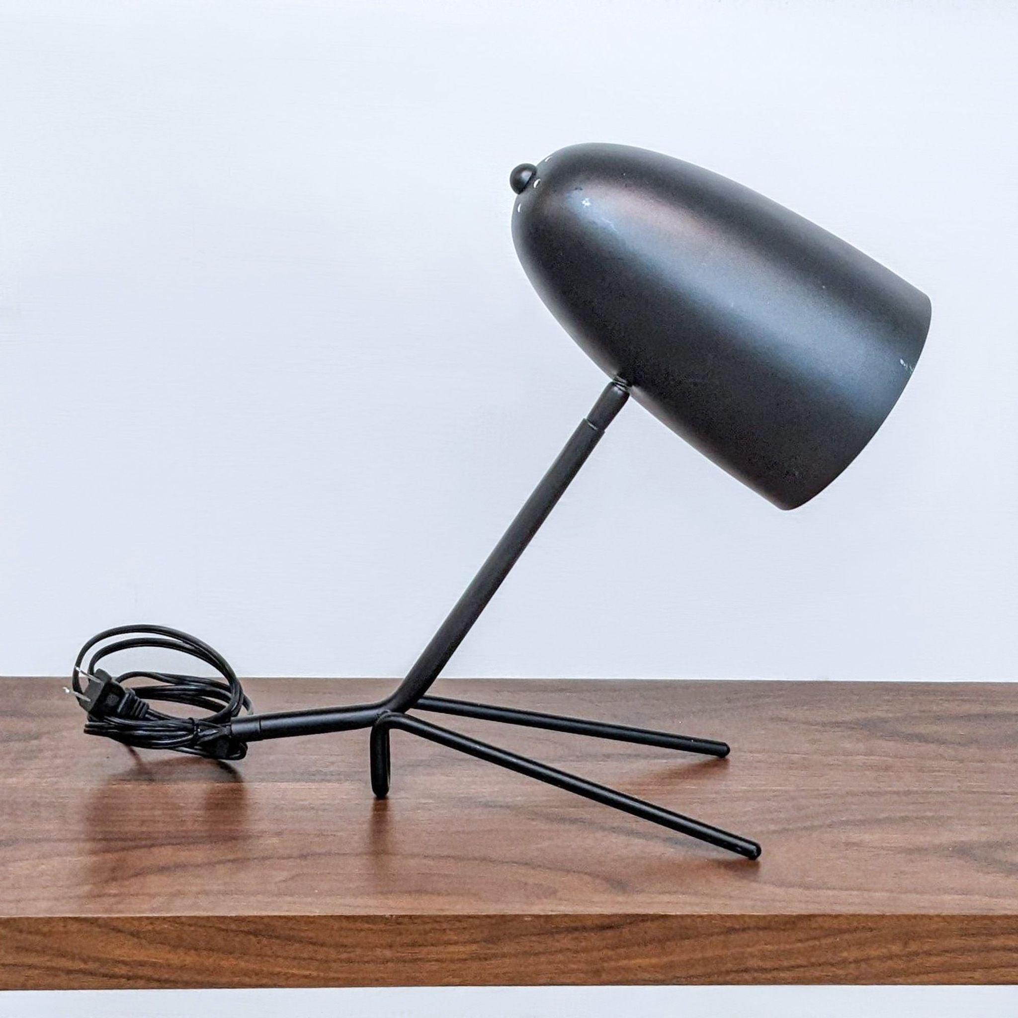 Reperch brand black desk lamp with an adjustable shade and tripod base on a wooden surface.