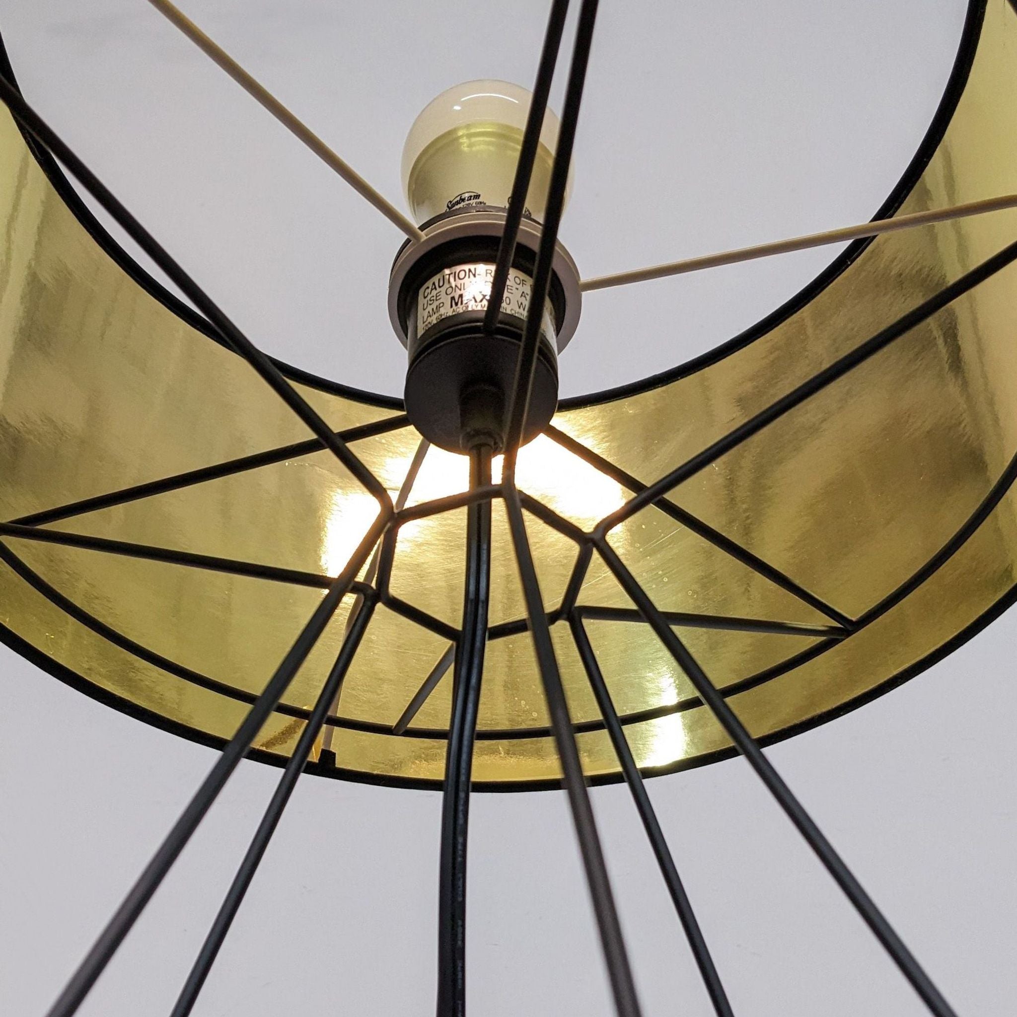 Close-up of Reperch lighting, showing light bulb inside a gold-lined black lampshade with a wireframe design.