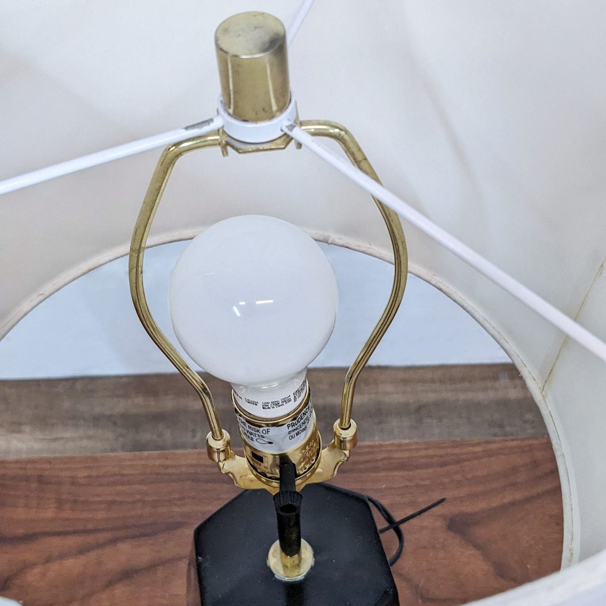 Interior view of Reperch table lamp showing white bulb and gold-tone metal details under shade.