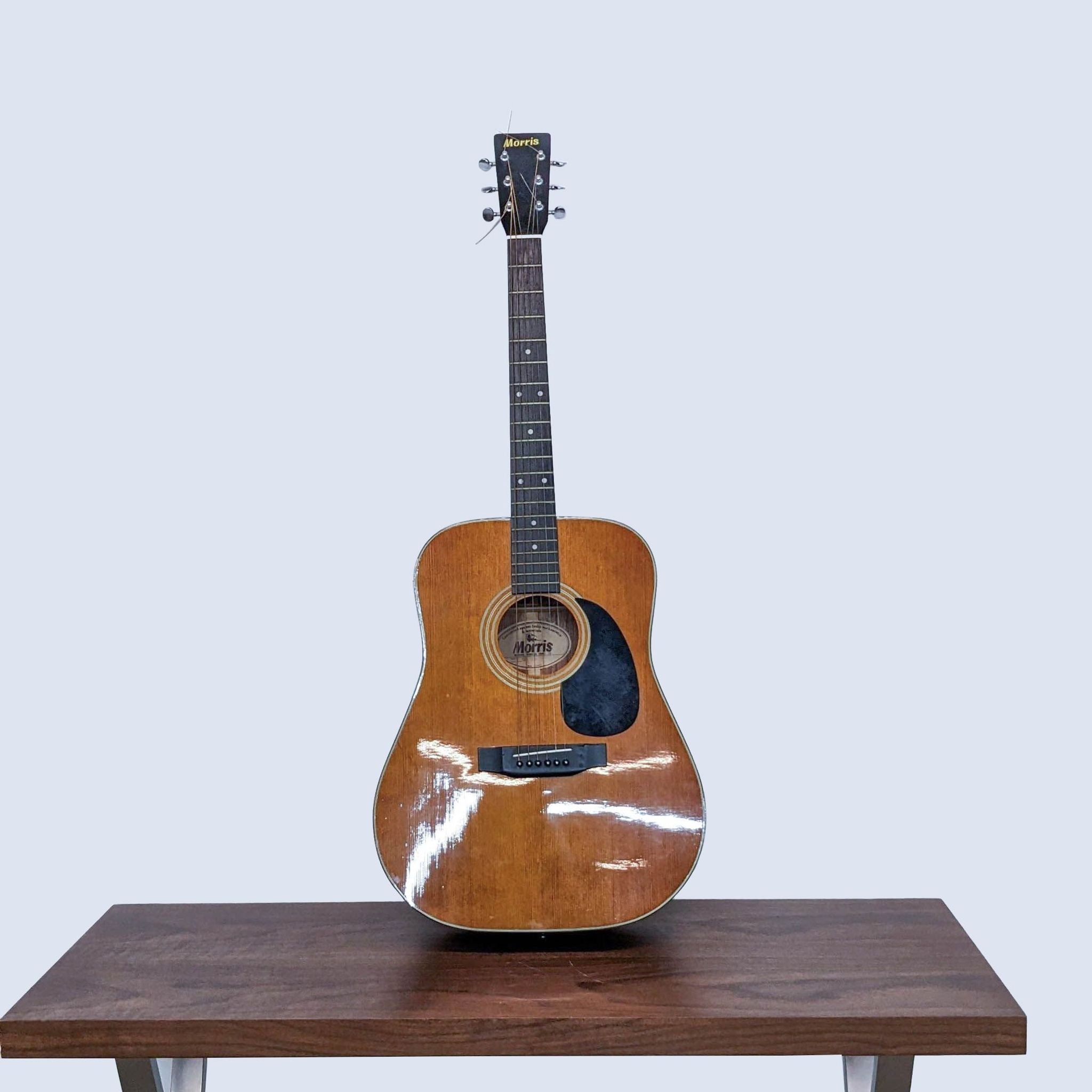 Closed guitar case standing on wooden table, grey background, exemplifying protection for an instrument like the Morris MD-51M guitar.
