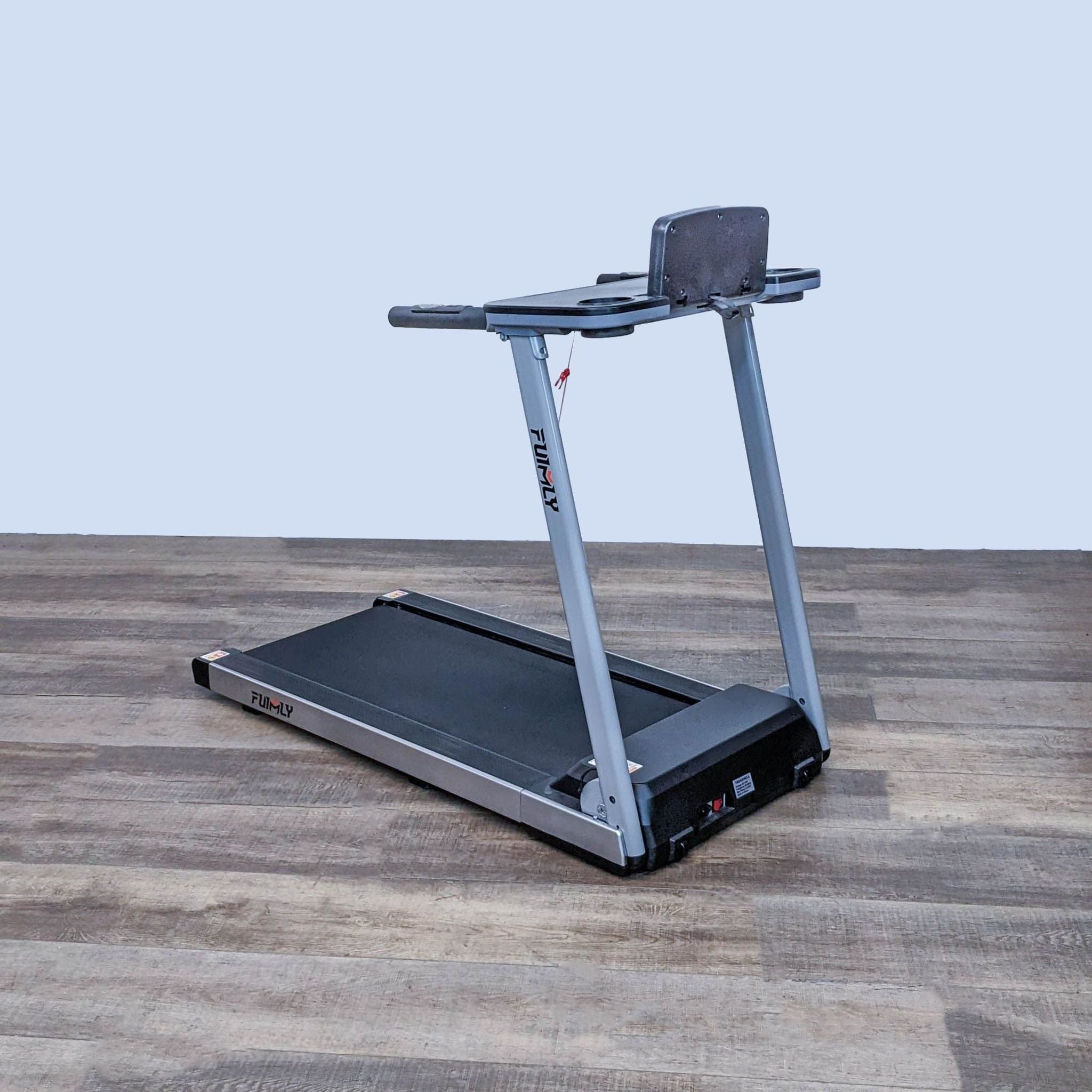 Alt: Compact Funmily brand treadmill on wooden floor, folded platform with grey support frame.
