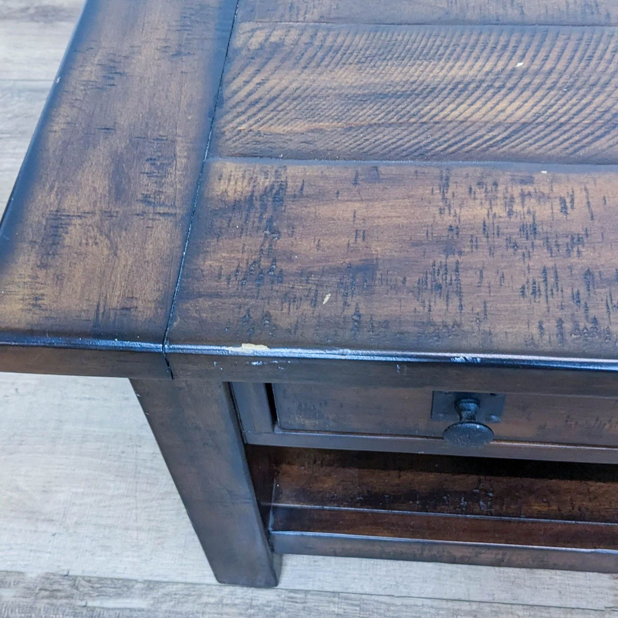 Reperch coffee table corner with planked wood top and metal drawer pull.