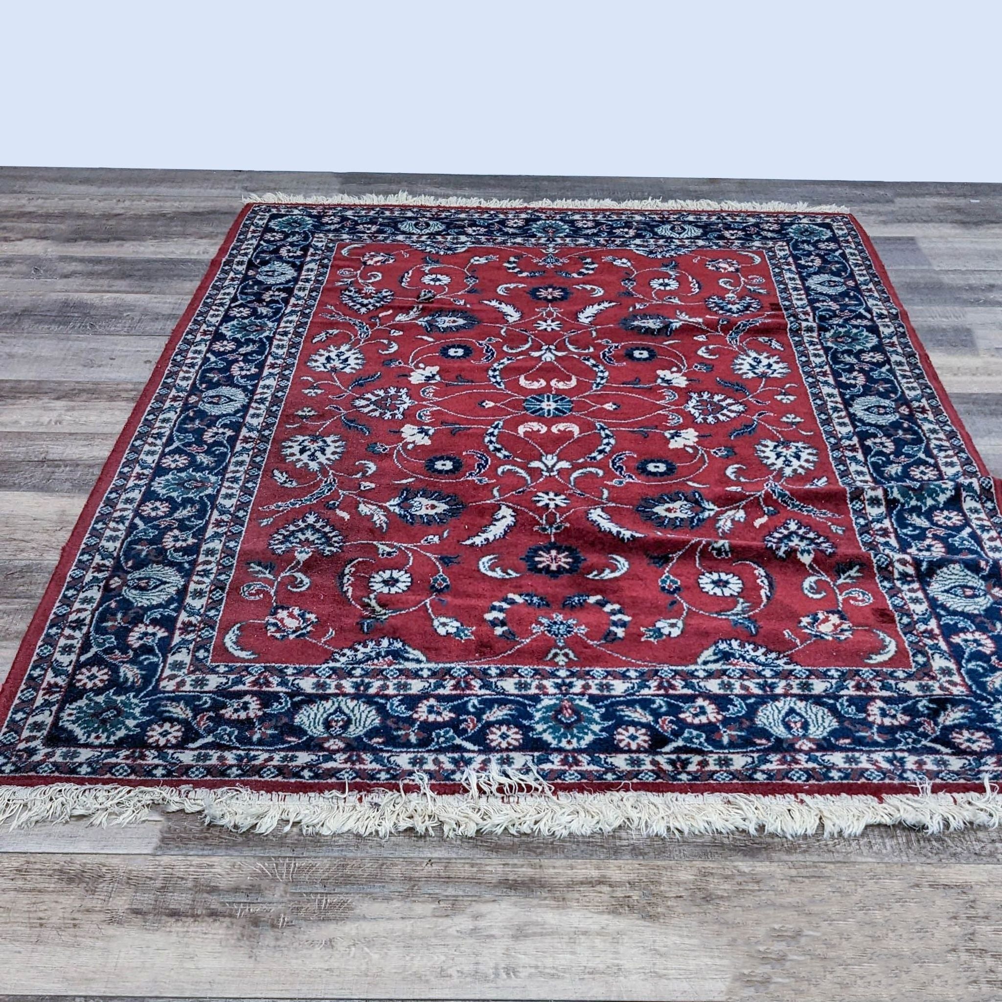 Reperch-branded 5'7"x8'4" oriental wool rug with red core, intricate blue and white patterns, and fringed edges.
