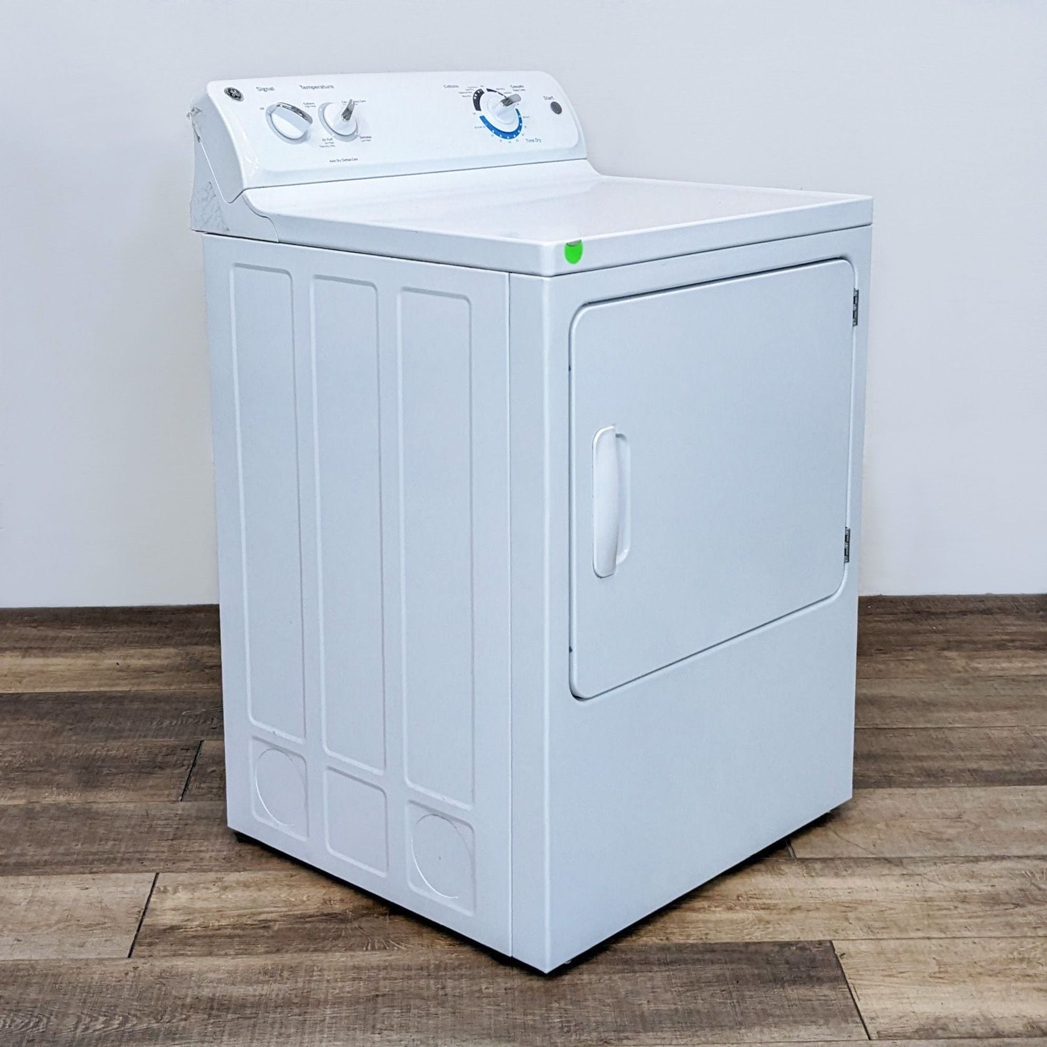 Side perspective of a GE washer/dryer with ribbed side panels on a wood floor.