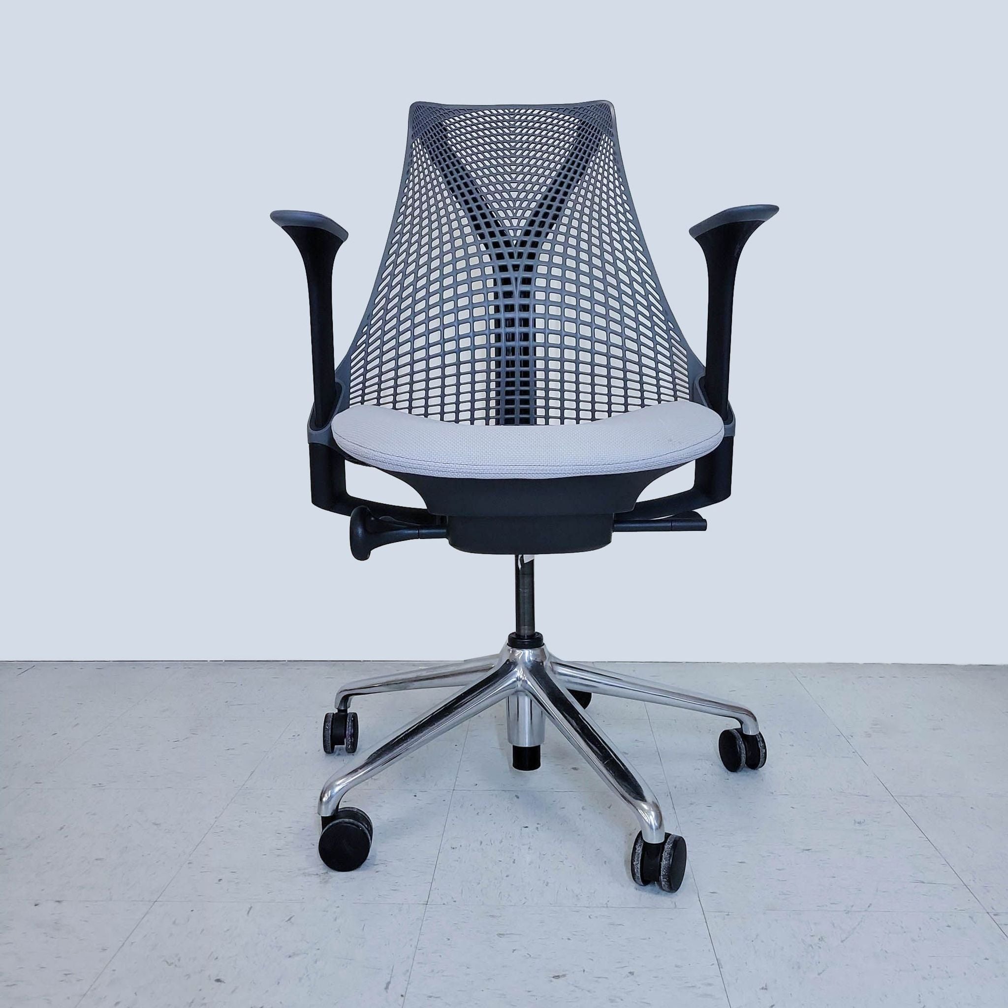 Herman Miller chair with a mesh back, armrests, and a five-star base with casters, on a grey background.