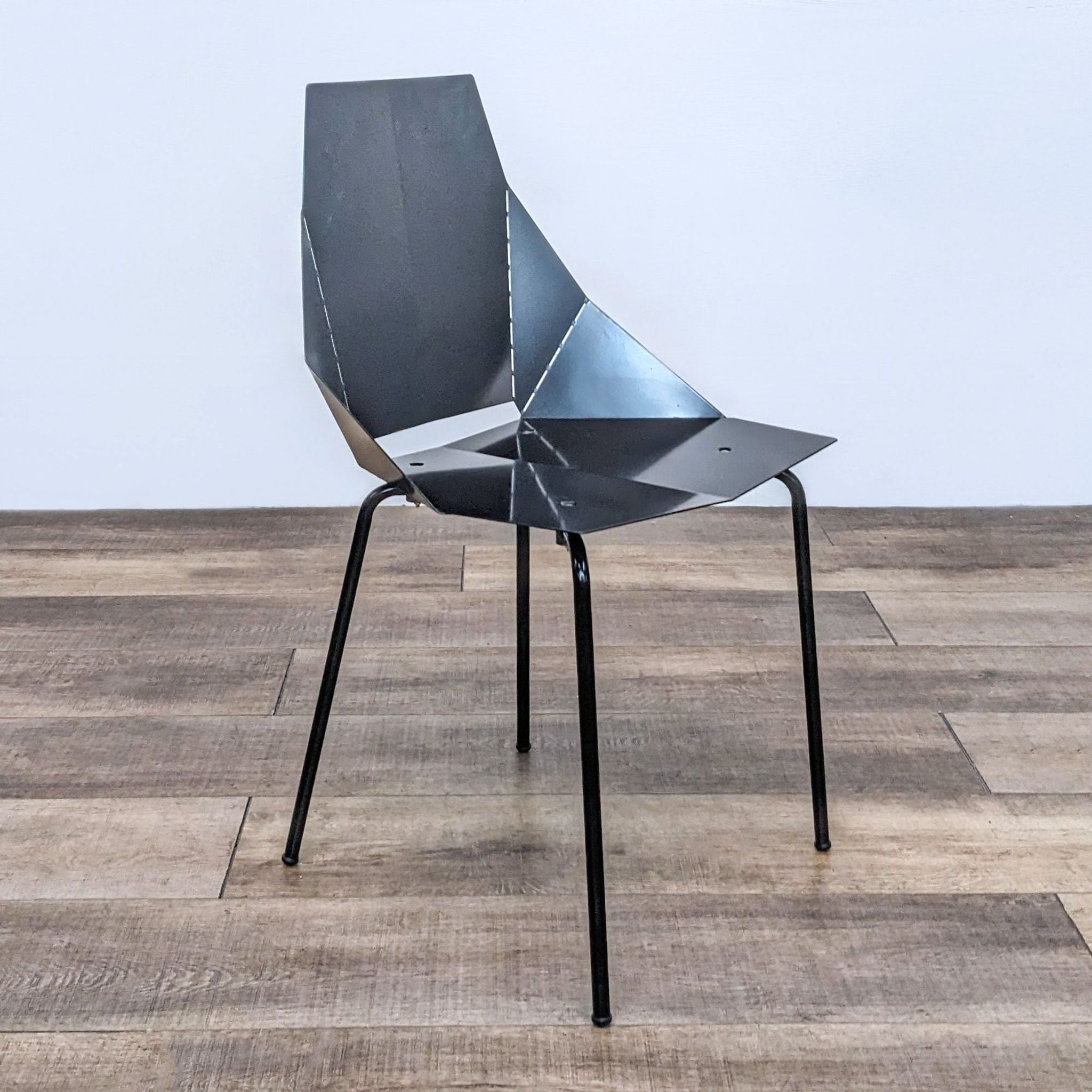 Blu Dot Real Good Chair in black powder coated steel with a geometric, industrial design, on a wooden floor.