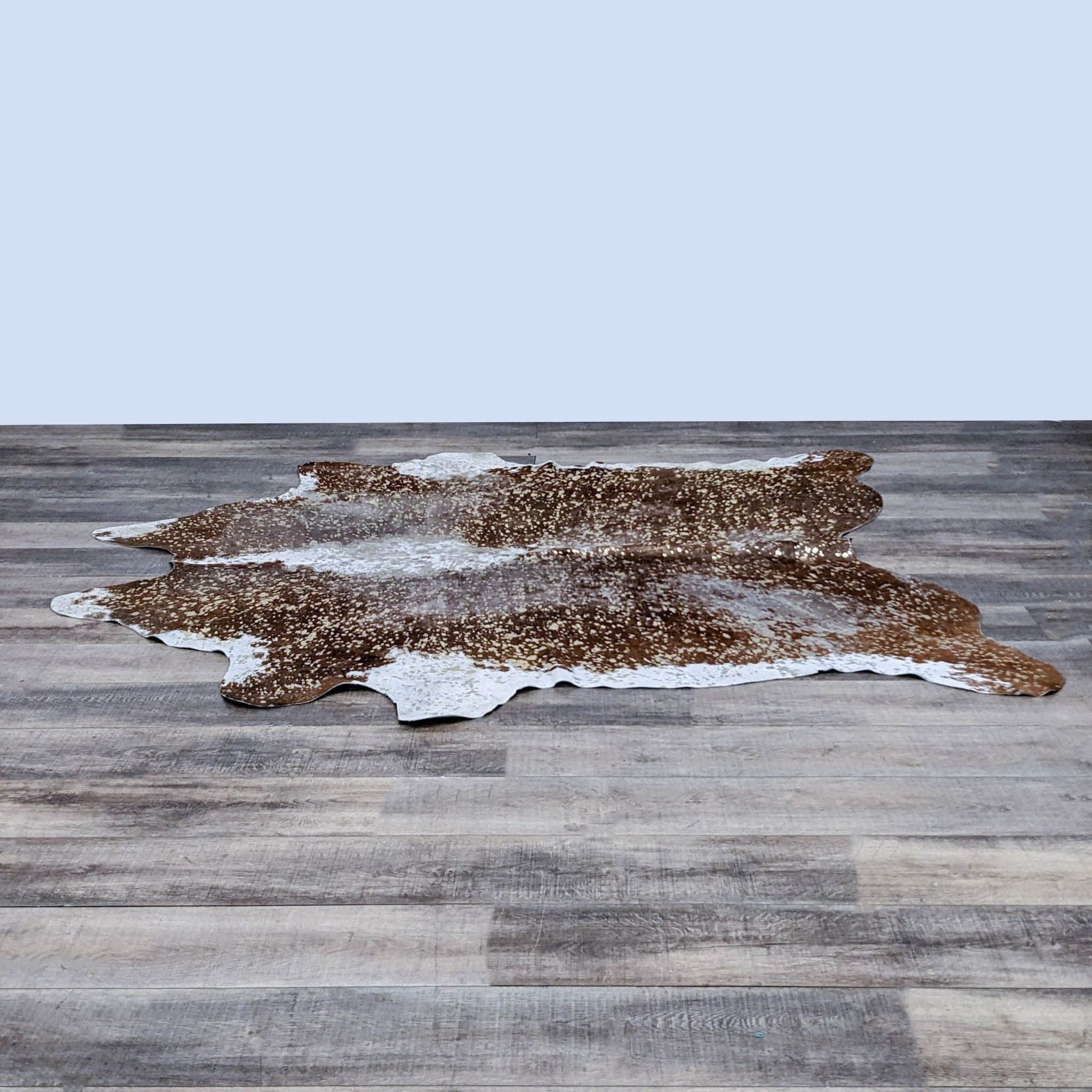 Gold and brown acid wash cowhide rug by Rustic Country Co on a wooden floor.
