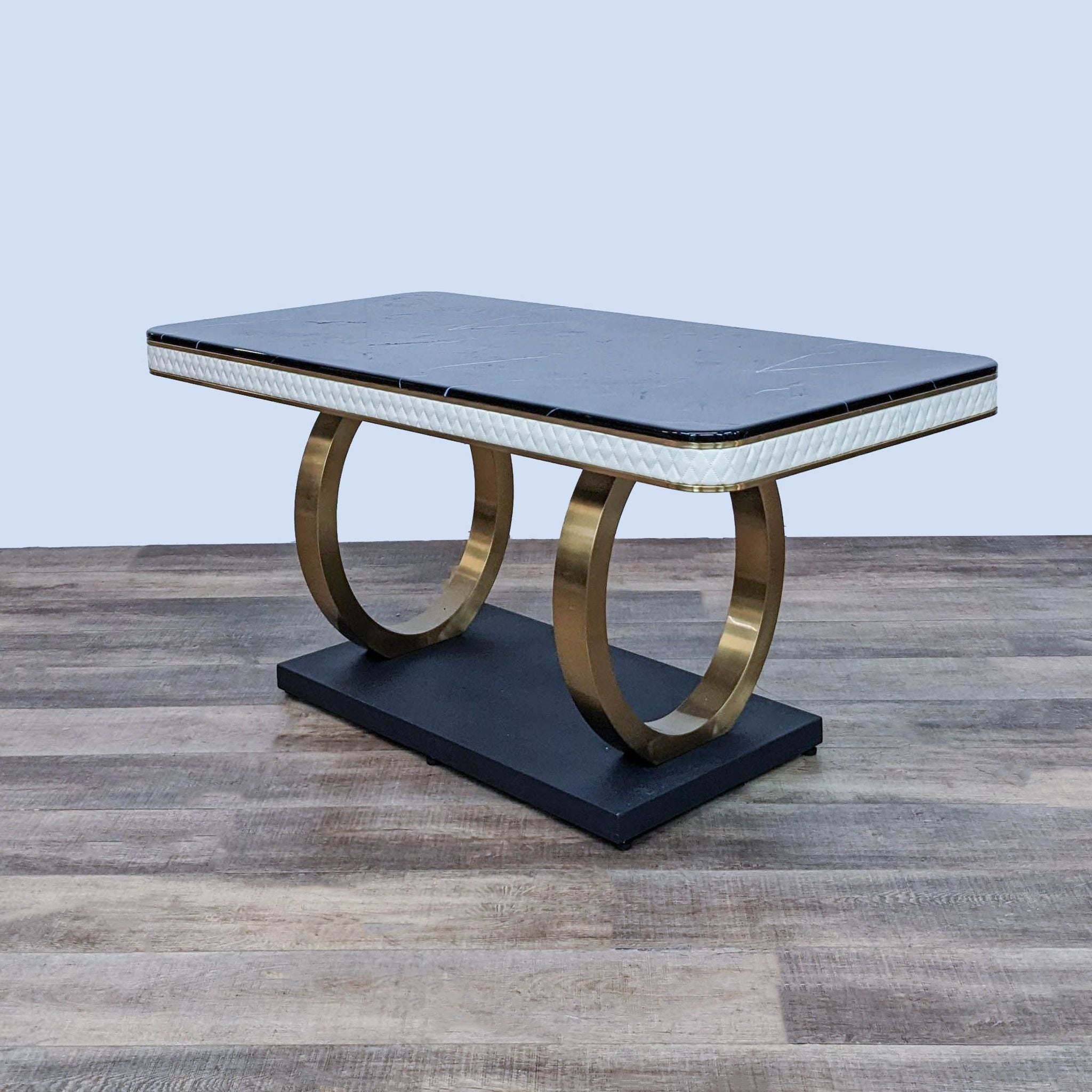 Everly Quinn Ingris dining table with a black marble top and gold metal edged double circle pedestal base with diamond tufted faux leather.