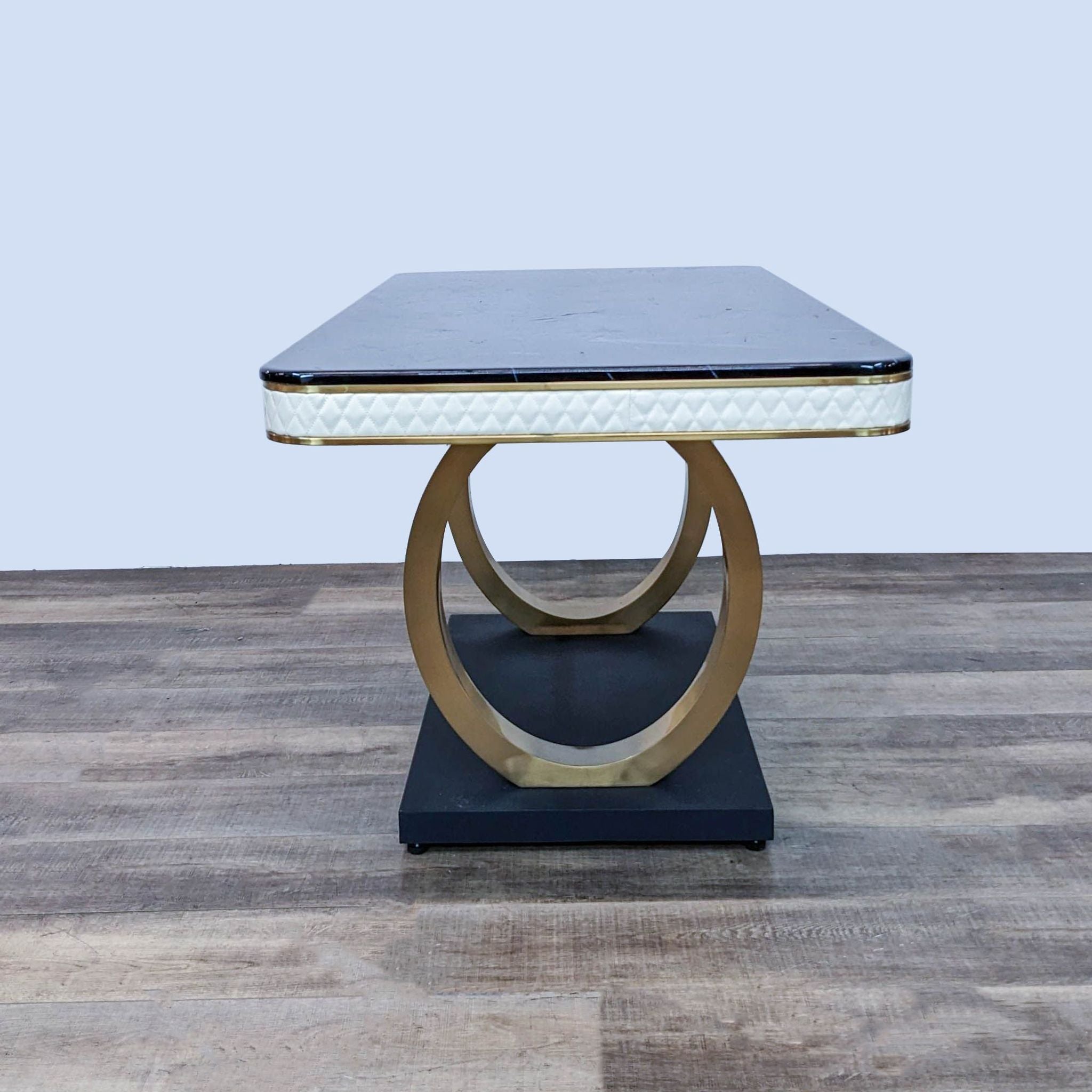 Modern Everly Quinn dining table with a black marble surface and unique double looped golden base, showcasing diamond-patterned edges.