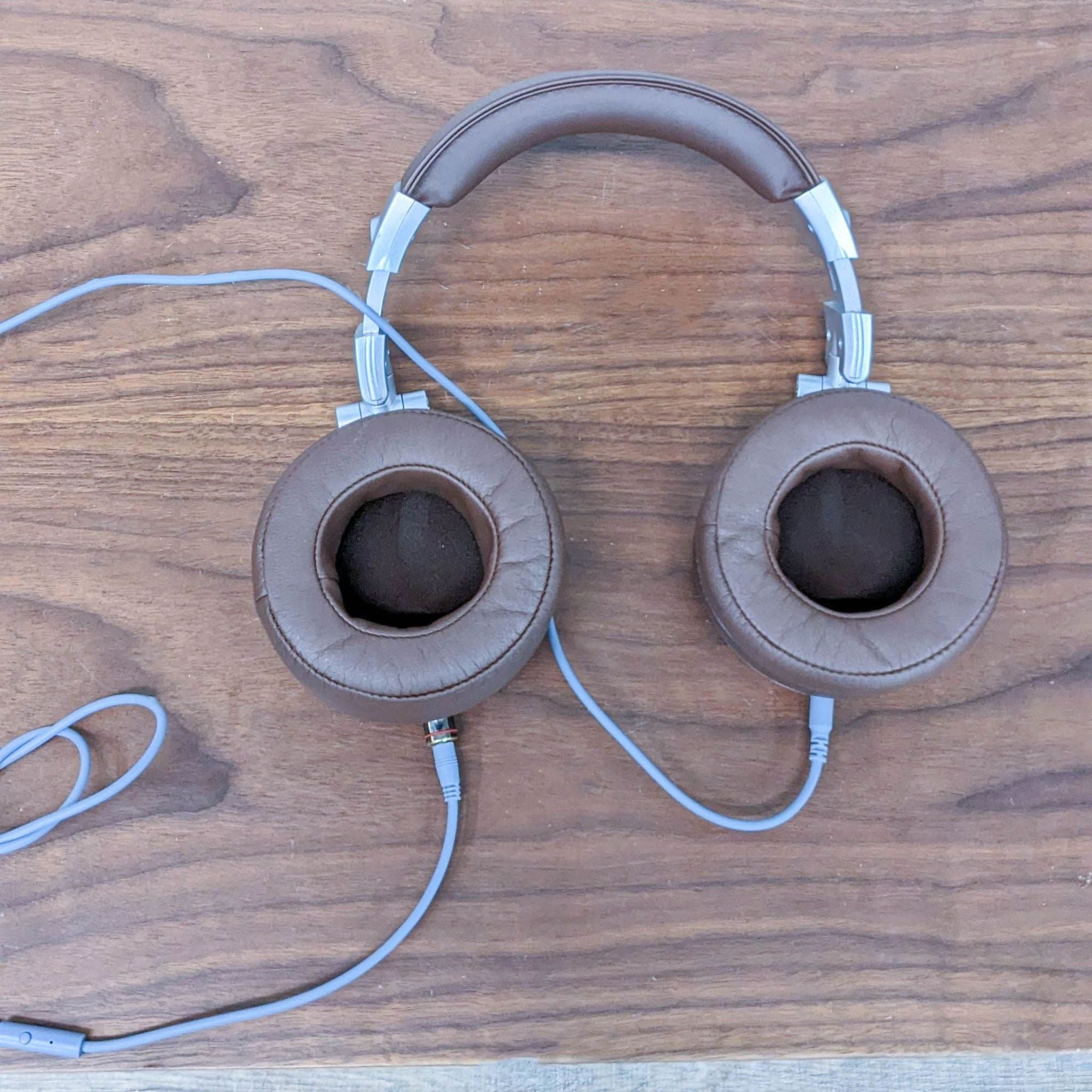 Brown leather cushioned OneOdio headphones viewed from top, showcasing comfortable ear cups, on wood.