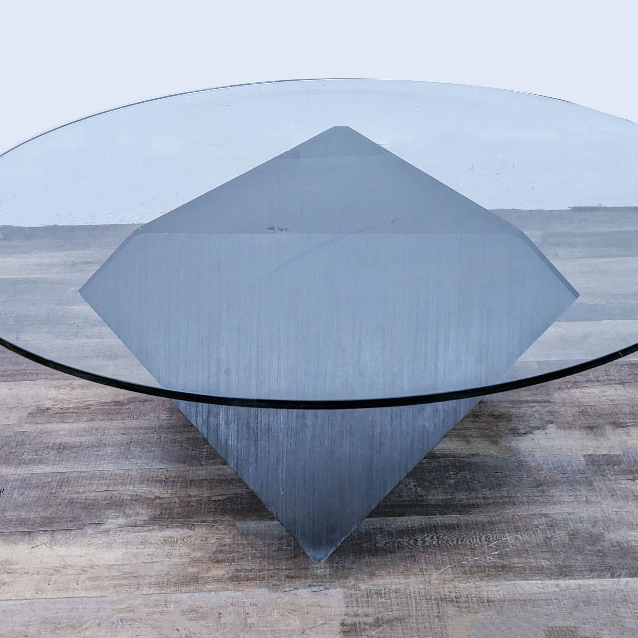 Aerial view of a round glass-topped Reperch dining table, showcasing its unique wood veneer geometric base.