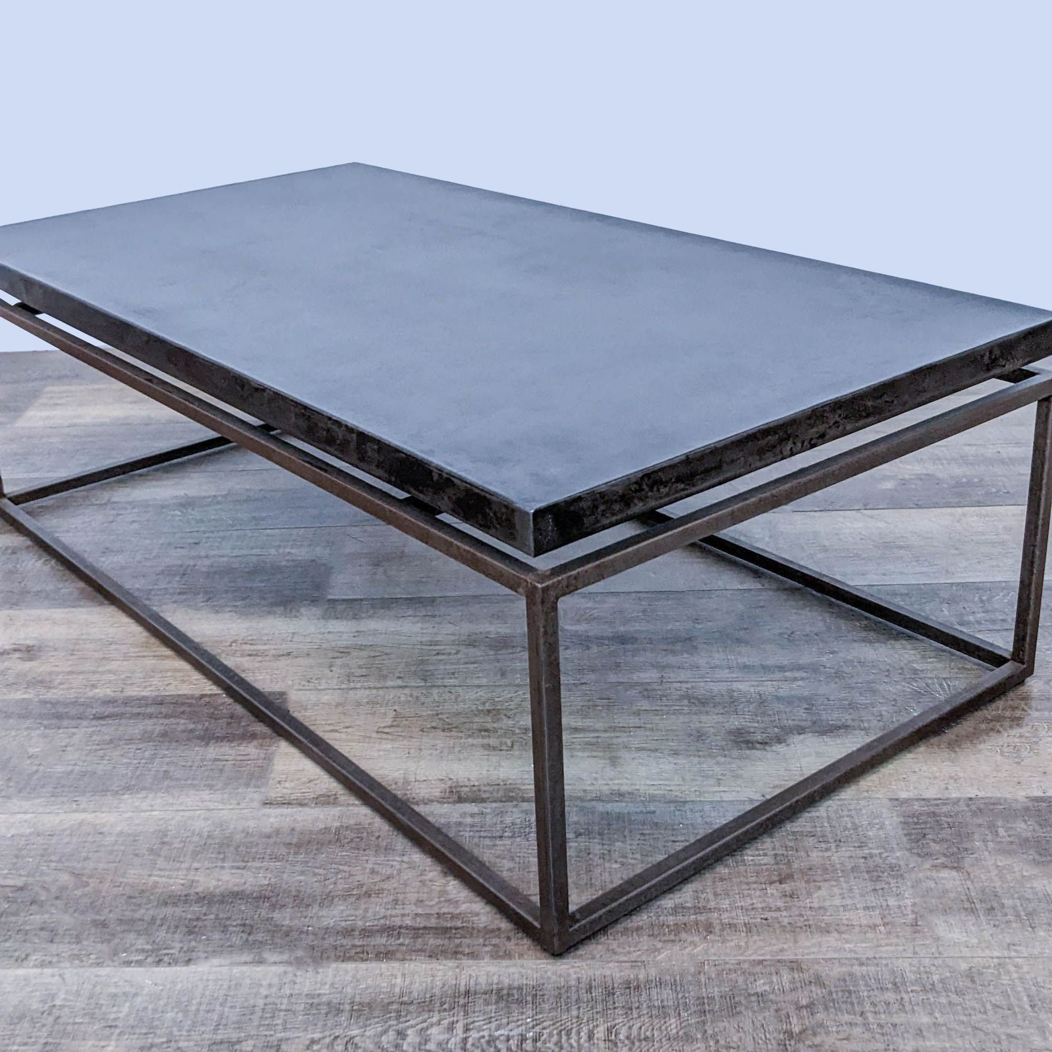 Reperch brand metal coffee table with a "suspended" top on geometric base on a wooden floor.