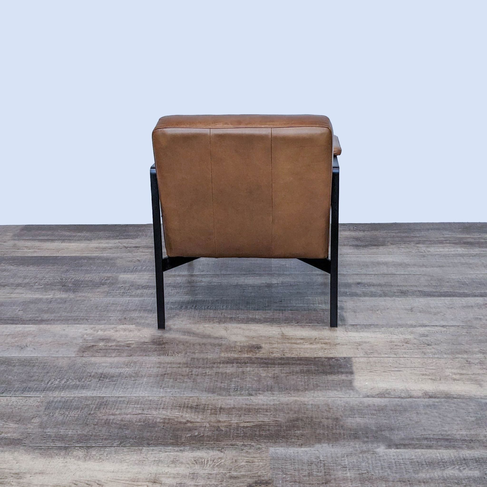 West Elm Highline chair with top grain leather seat and padded arms on a steel base, FSC-certified wood frame, on wooden floor.