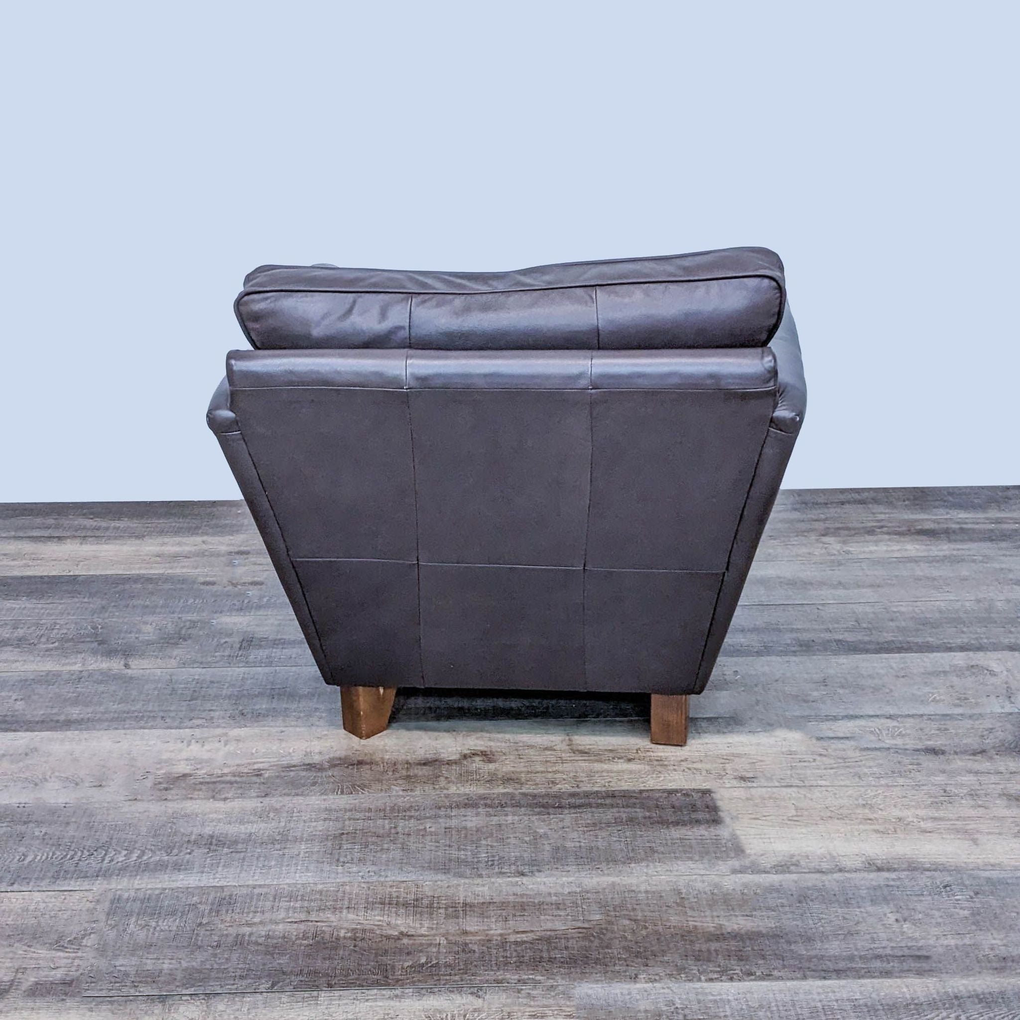 Marks & Spencer contemporary dark leather armchair with tapered wooden feet, viewed from the back.