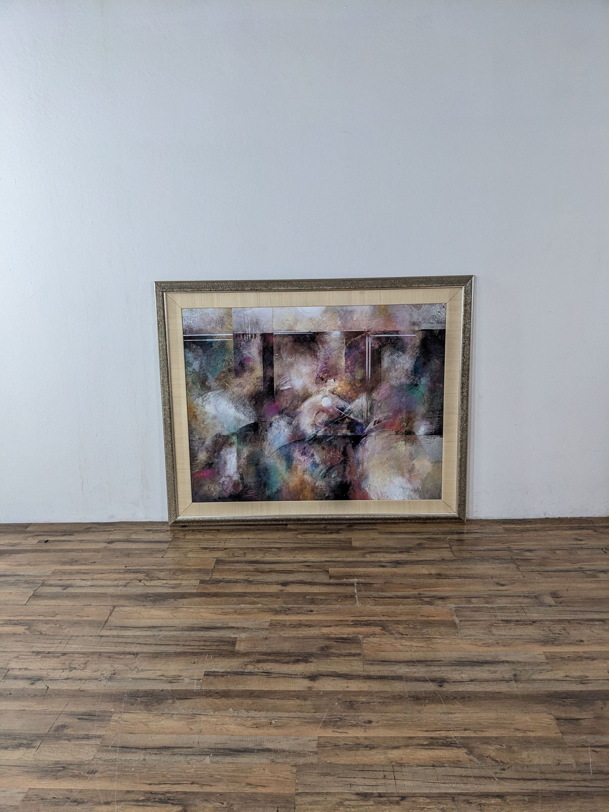 Colorful abstract painting by Douglas in a golden frame, displayed on a wooden floor against a white wall, Reperch brand.
