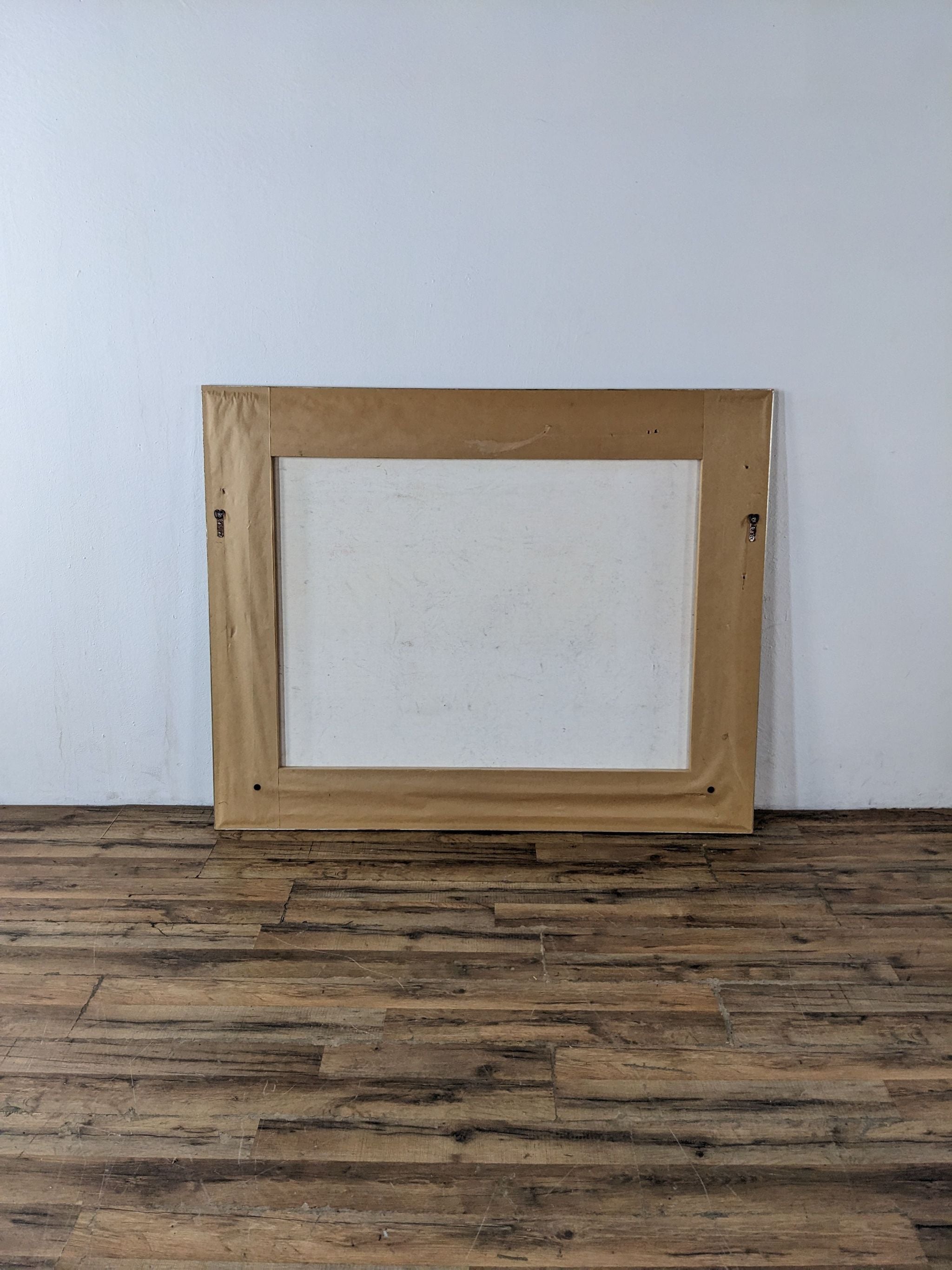 Back view of a canvas on a wooden floor against a white wall, signed by artist Douglas, from Reperch brand.