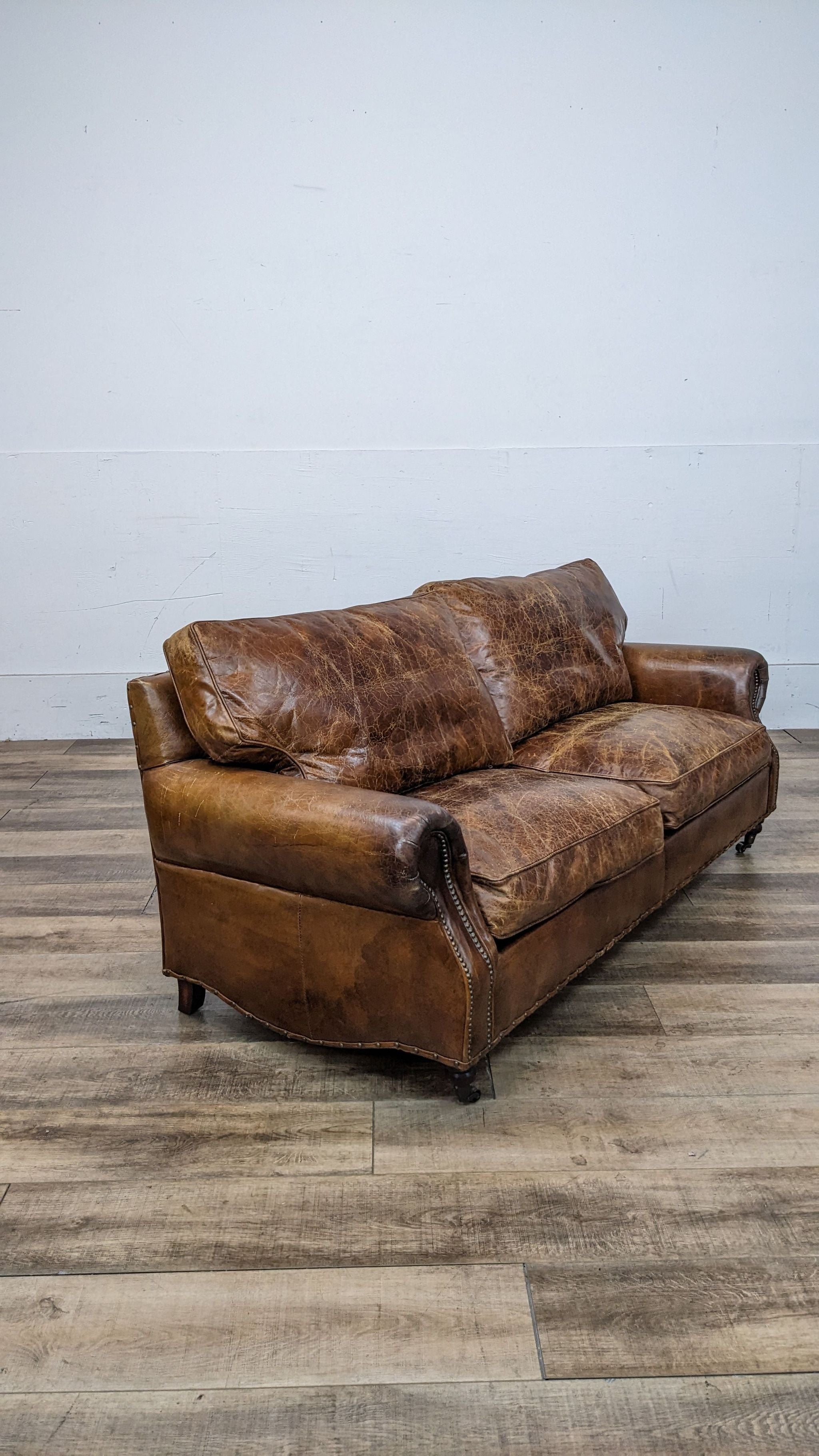 Frontal view of a Reperch contemporary cognac leather sofa, showing a worn patina and classic design.