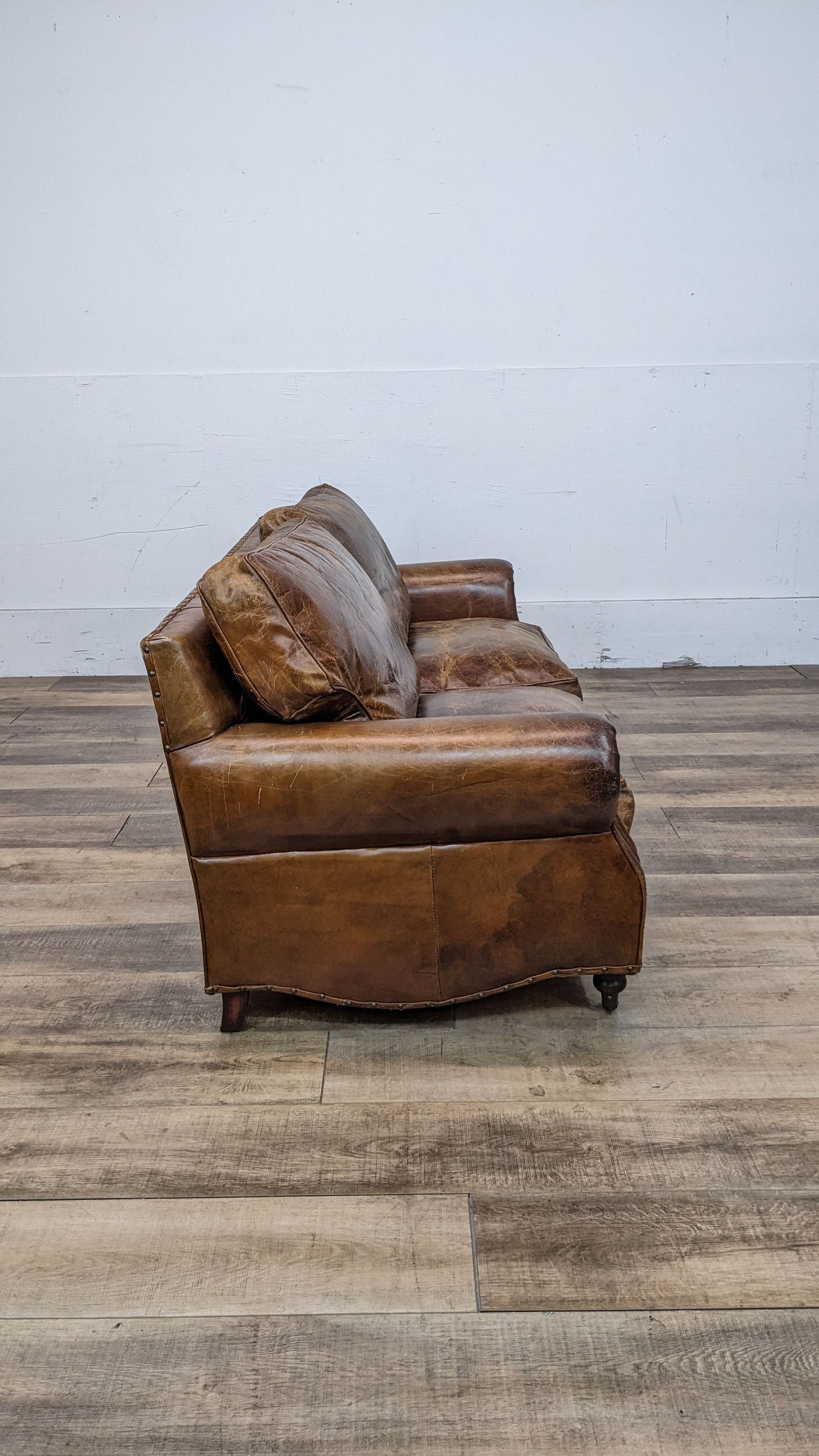 A side angle of a distressed leather loveseat by Reperch, exemplifying timeless Ralph Lauren style.