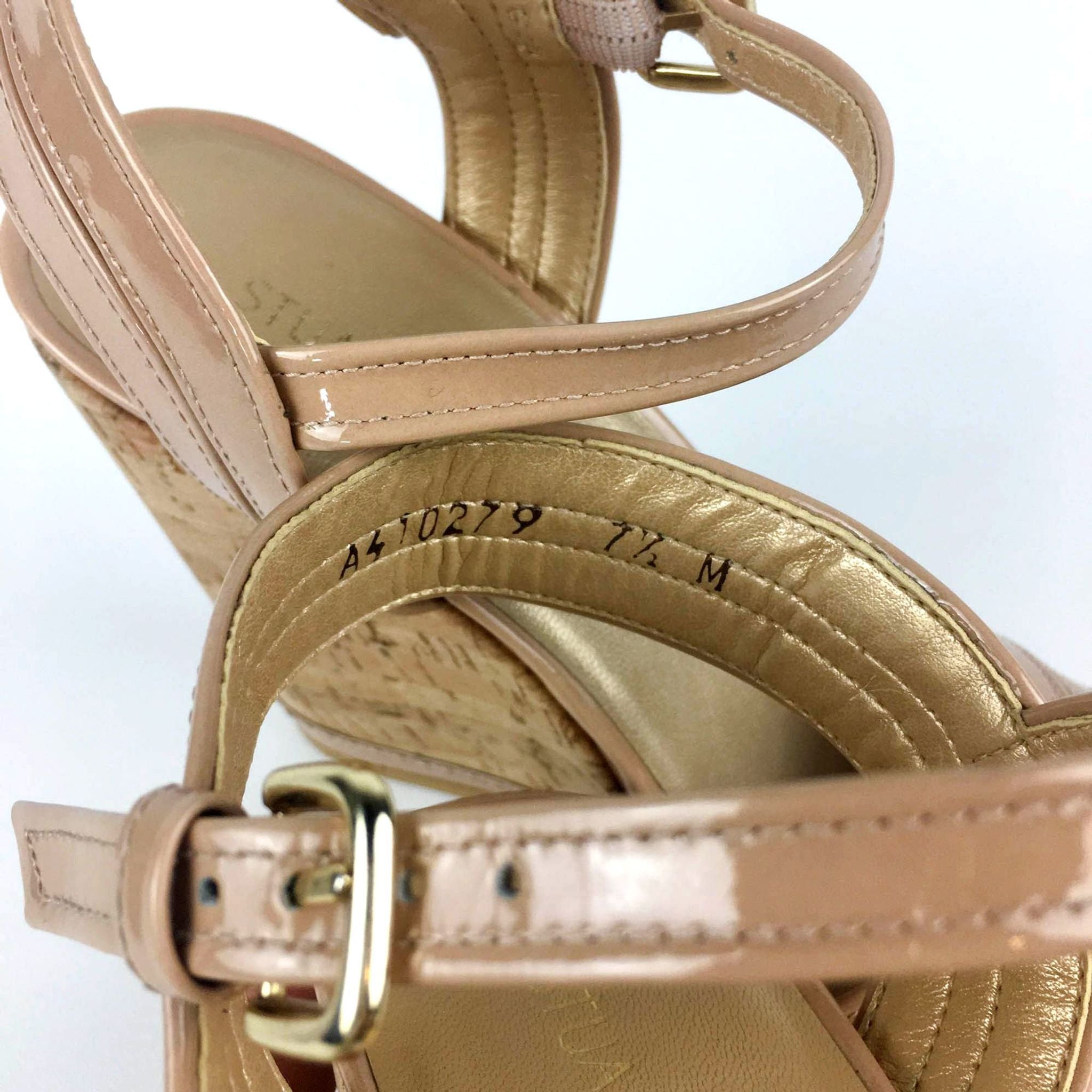 3. Detail view of beige Stuart Weitzman ankle strap wedge heel showing size label and patent leather texture.