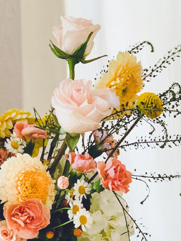 A detail shot of a mixed arrangement of warm pastel flowers