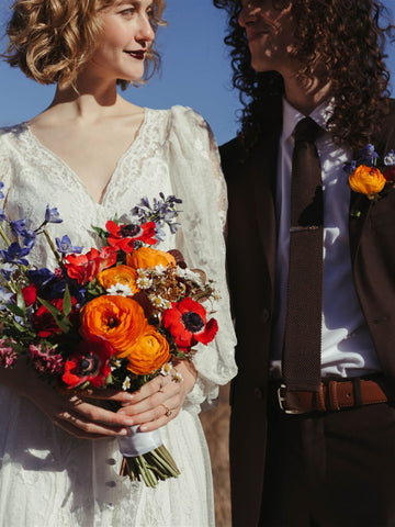 Bride and groom outside with a colorful bouquet of flowers.