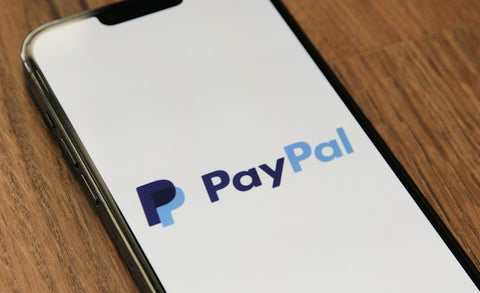 photo of a mobile phone on a wooden desk with paypal app open