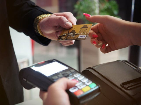 photo of a man handing a woman a gold visa credit card