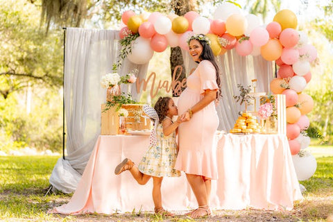outdoor baby shower with a young girl kissing a pregnant woman's stomach