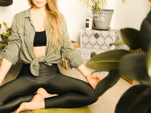 Plants can reduce stress. Woman meditating in a room that contains a lot of plants.
