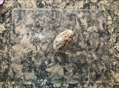 A ball of uncooked boba dough sits on a glass cutting board on a marble kitchen counter