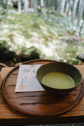 A bowl of Japanese green tea is on tray overlooking woods