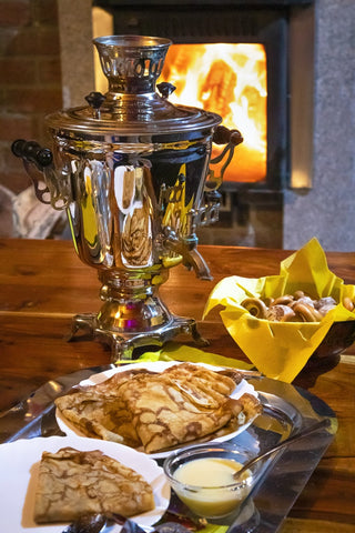 A Samovar of tea is on a table with sweet treats