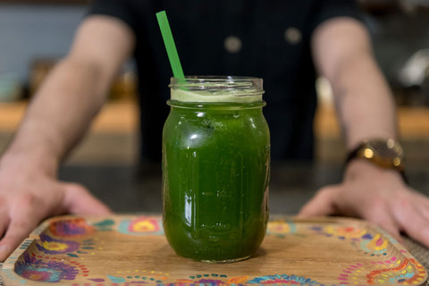 iced matcha green tea in a mason jar being presented on a tray