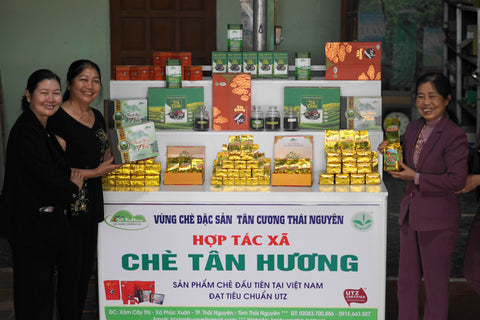 Workers from a tea plantation in Thai Nguyen province stand in front of a table with their products