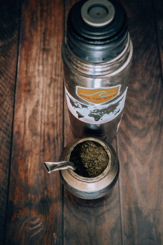 A gourd of yerba mate sits on a table with a bottle of water