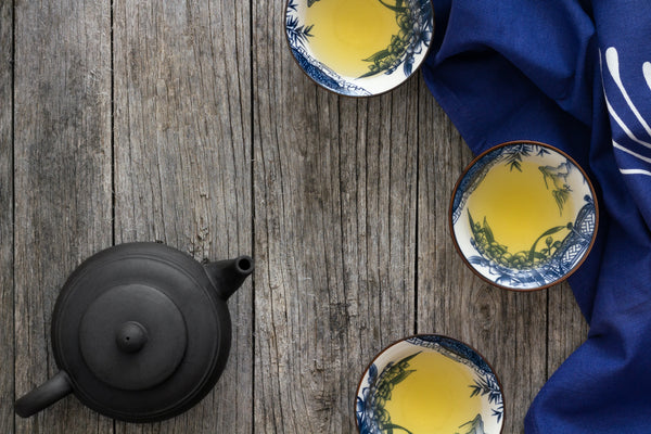 green tea in white and blue floral print cups on weathered wood background