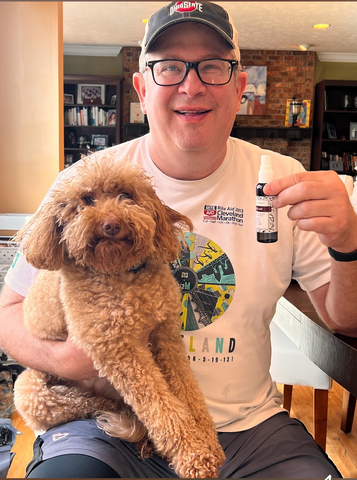 Man holding cute dog and bottle of Blaze Away.