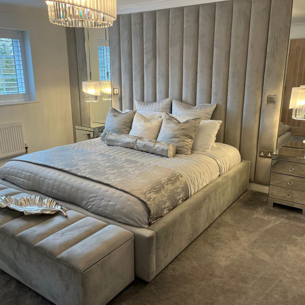 Luxurious bedroom with double ottoman bed frame, silver bedding, and tufted headboard.