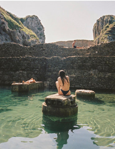 Lazy Summer days. Bathers sitting on rocks in a beautiful natural water hole.