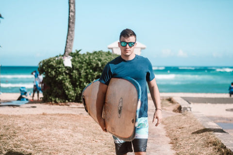 male surfer carrying a surfboard