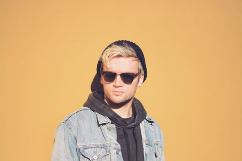 blonde male in sunglasses wearing hoodie yellow background