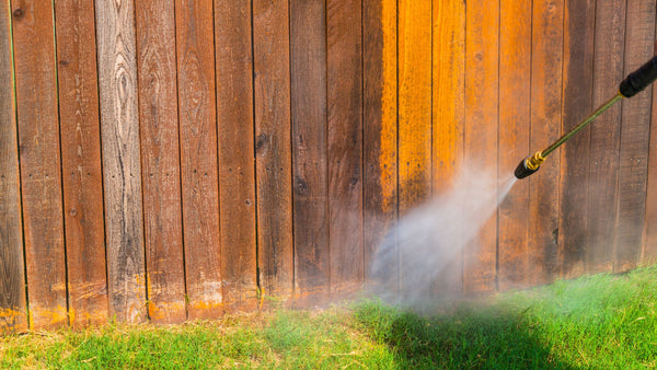 cleaning a wooden fence with pressure washing.