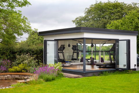 A garden room gym in cheshire in a garden with a pond