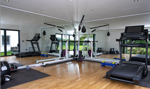 A garden room gym with tread machines and mirrors.