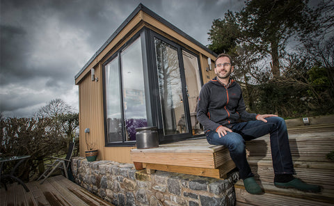 A garden office in north wales with a man sitting on a deck.