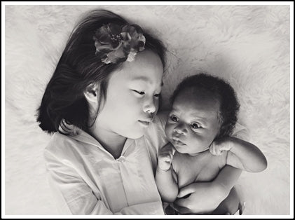 Happy child lays with newly adopted infant on bed