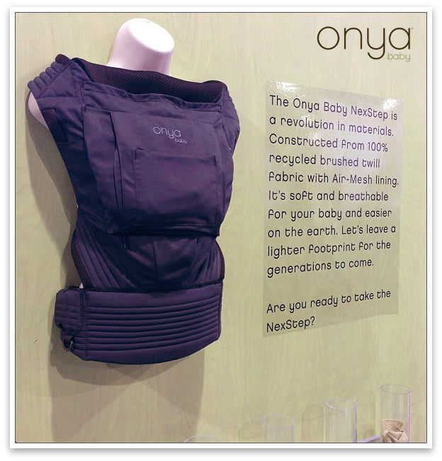 The Onya Baby NexStep baby carrier hung with information next to it