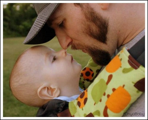 Father touching noses with his child in an Onya Baby Carrier