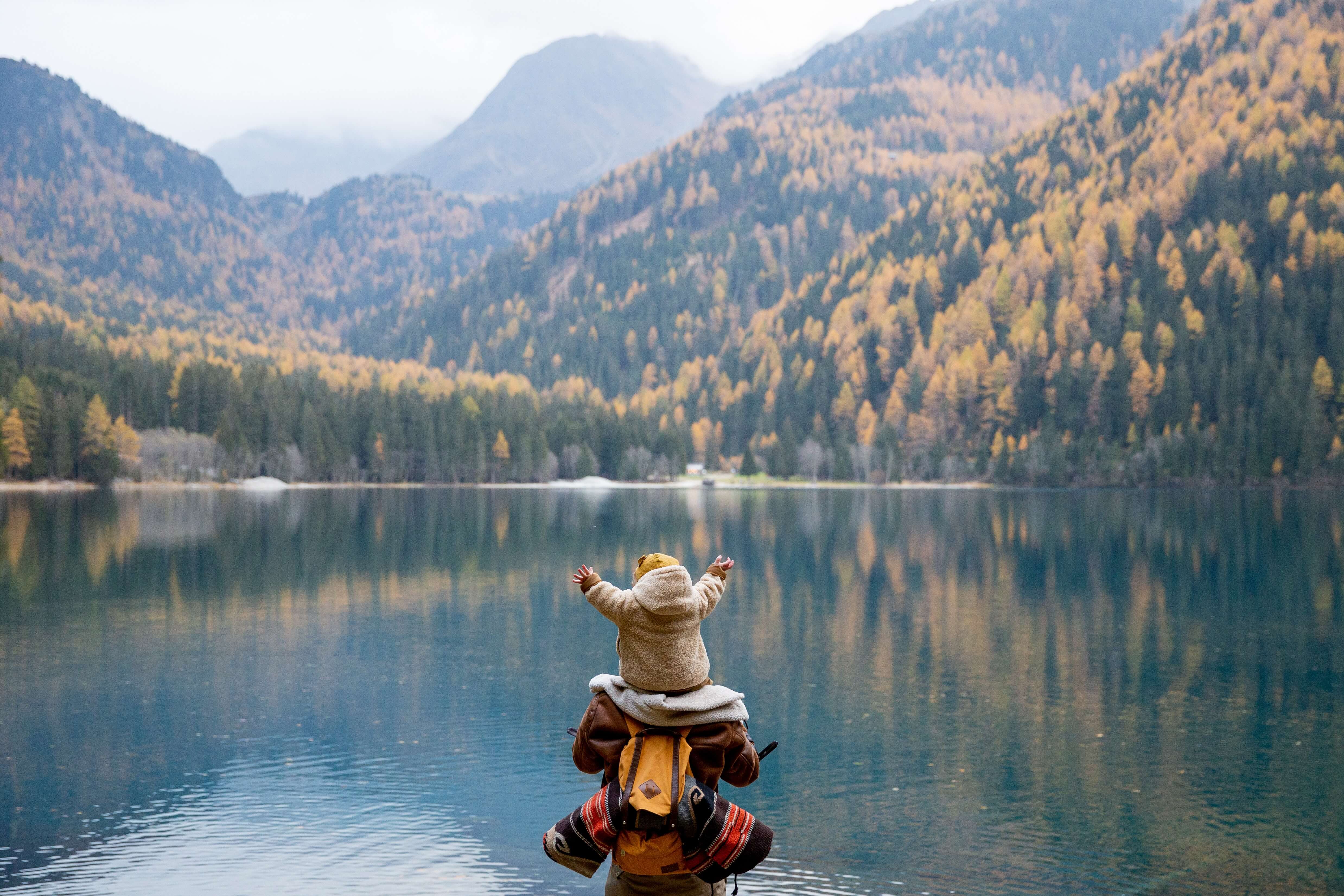 Baby looking at lake with both hands in the air